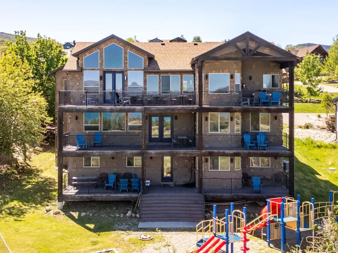 Multi-level residence featuring extensive outdoor decking, large windows, and a dedicated outdoor play area