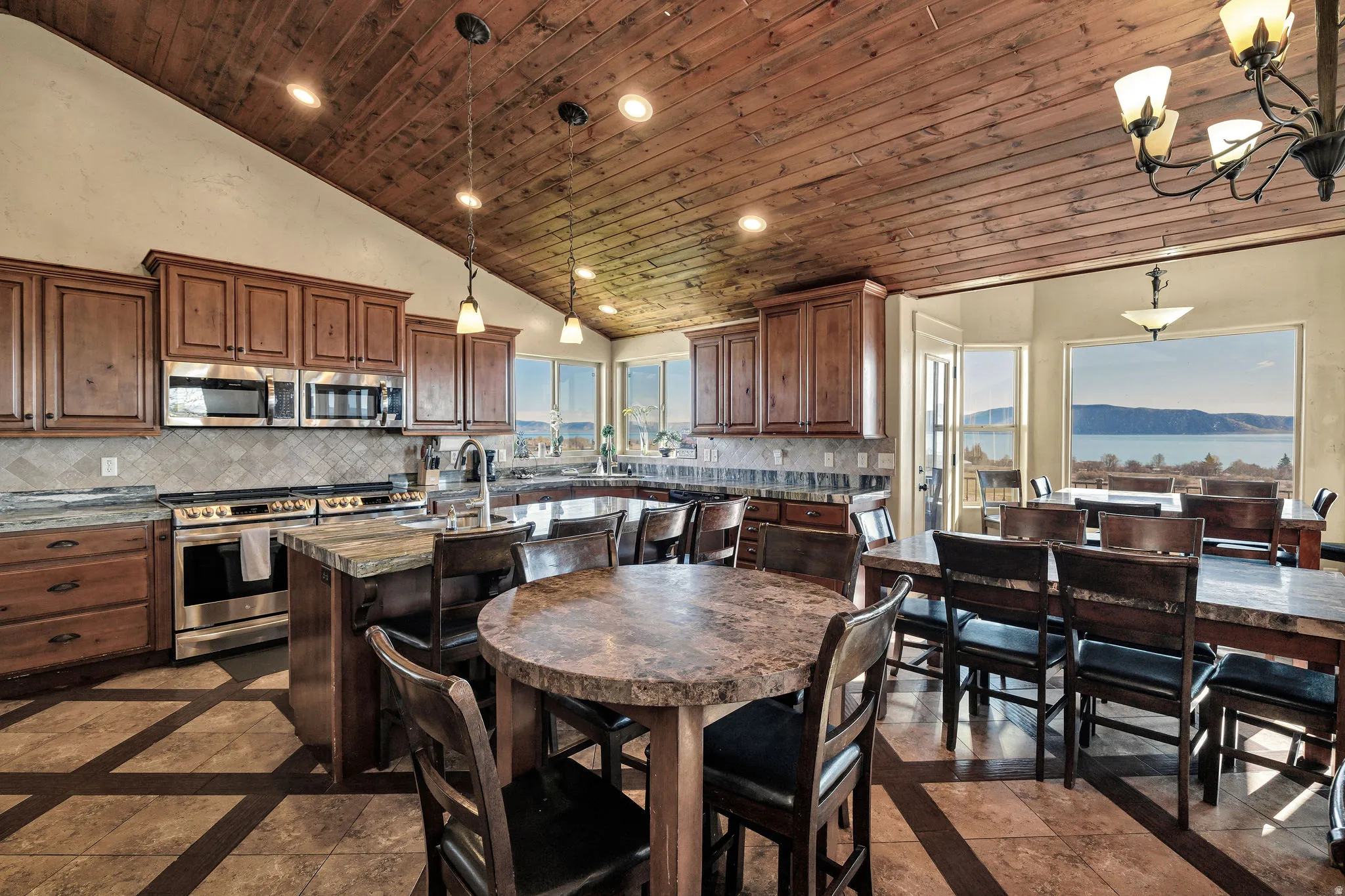 Open-concept kitchen and dining area featuring a vaulted wood-paneled ceiling, stainless steel appliances, and abundant natural light