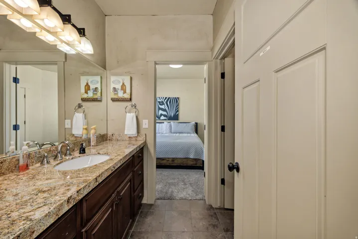 Bathroom vanity featuring a polished stone countertop, undermount sink, and dark wood cabinetry