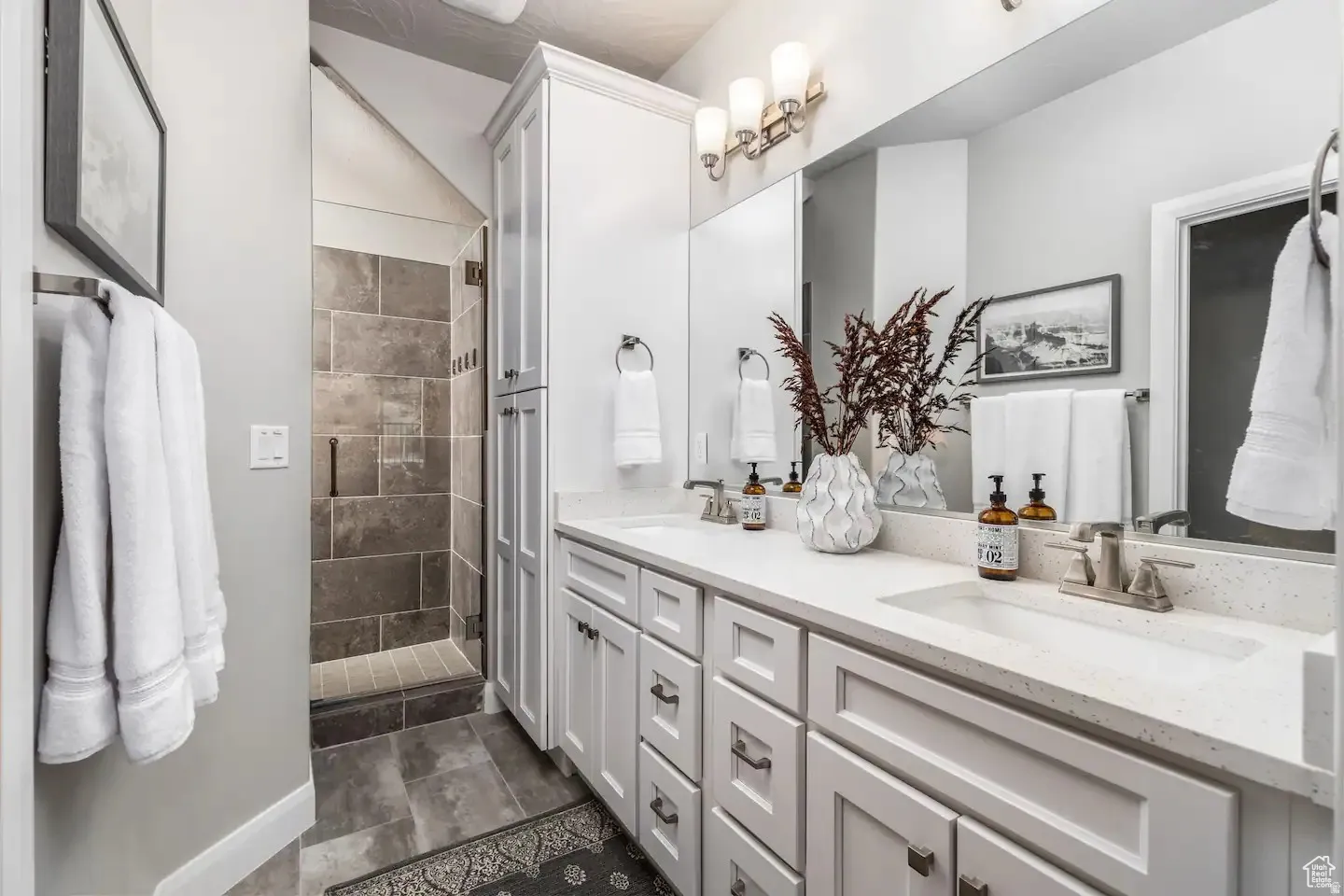 Bathroom featuring a dual vanity with white cabinetry, integrated sinks, and light-toned countertops