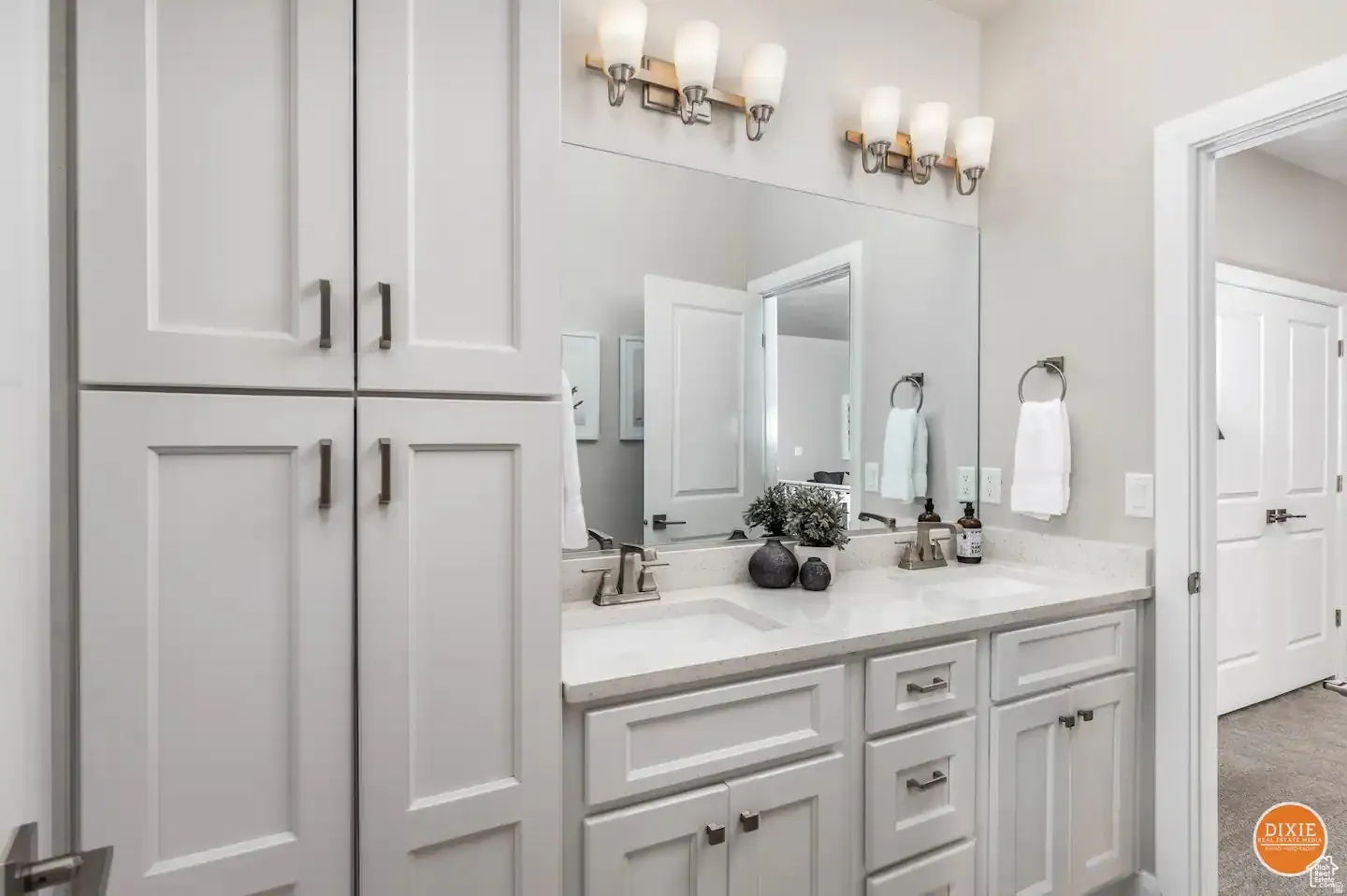 Dual sink vanity with white cabinetry, light-toned countertops, and brushed nickel hardware