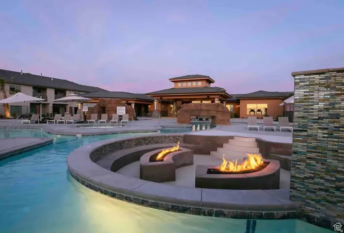 Resort-style pool area featuring multiple fire pits, a stepped concrete seating area, and a flowing water feature
