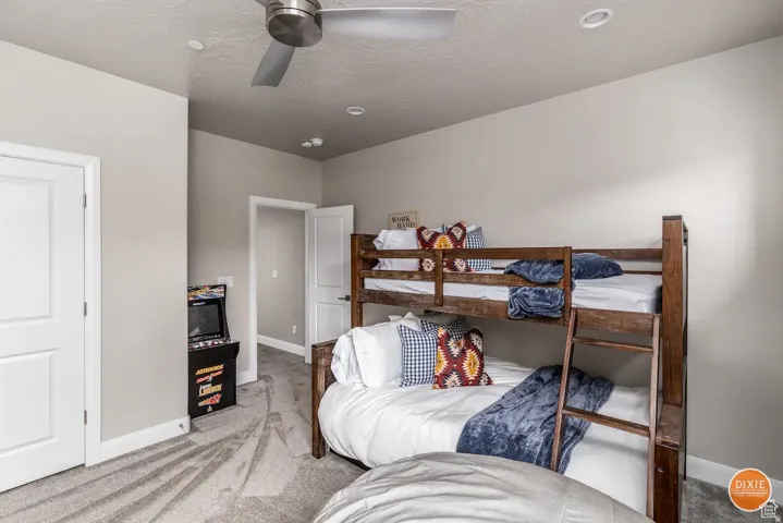 Room featuring light gray walls, gray patterned carpet flooring, and a ceiling fan with integrated lighting
