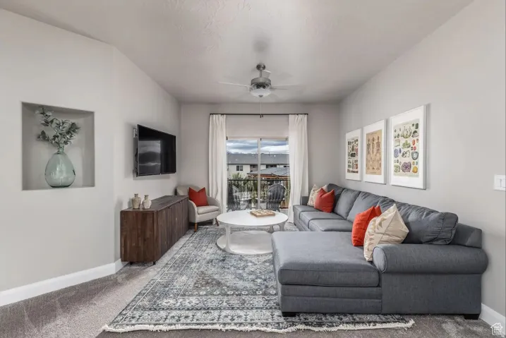 Living area featuring a built-in wall niche, ceiling fan, and access to an outdoor balcony