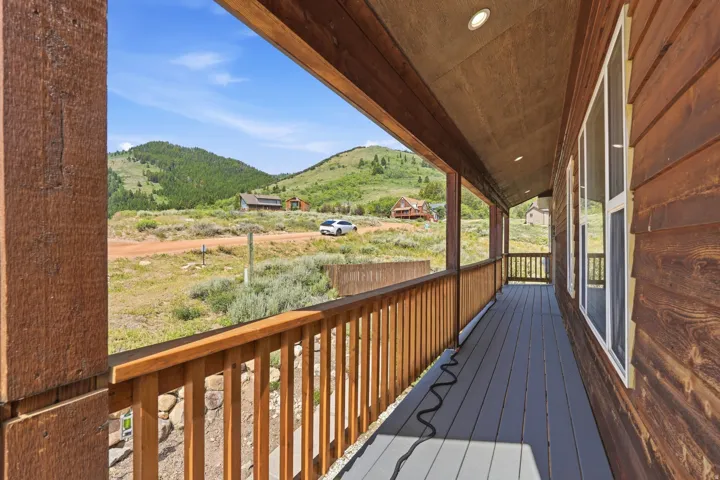 Expansive covered porch featuring wood-finish decking and natural wood railings