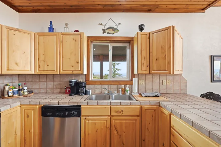 Kitchen featuring natural wood cabinetry, tile countertops, and a tile backsplash