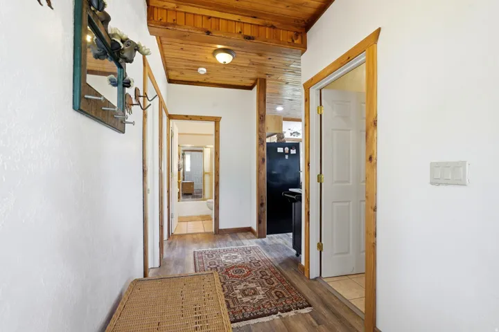 Hallway featuring wood-finish flooring, white walls, and a wooden tongue-and-groove ceiling