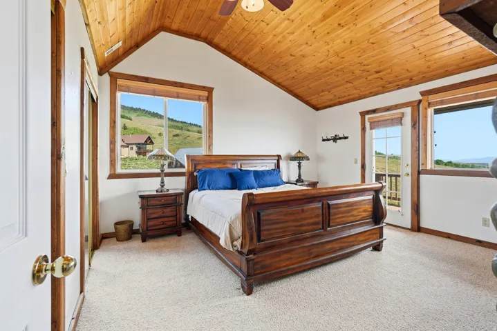 Vaulted wood-paneled ceiling with a ceiling fan, white walls, and light-toned carpeting
