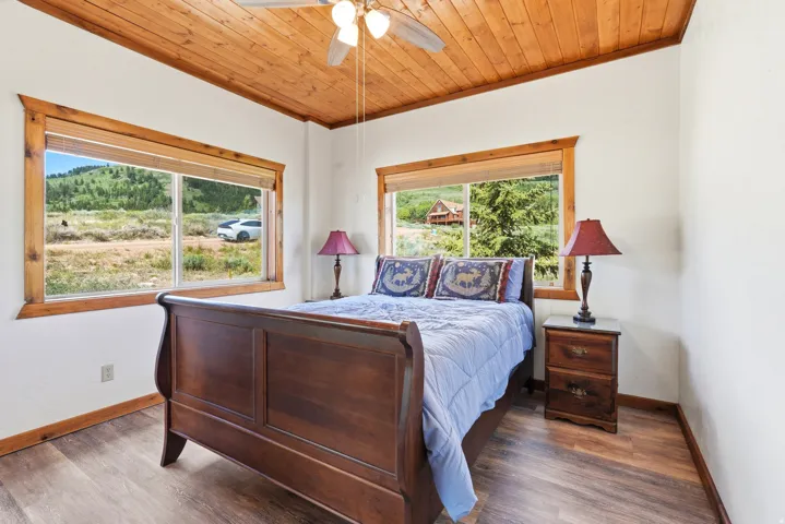 Room featuring a natural wood planked ceiling, wood-finish flooring, and white painted walls