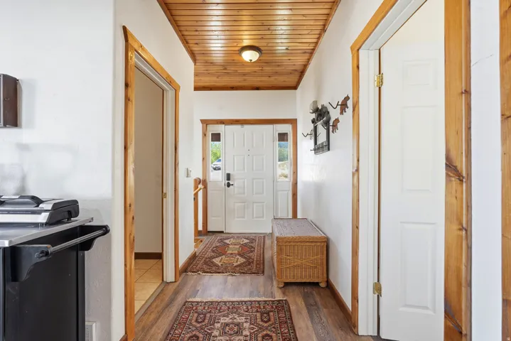 Entryway featuring wood-finish flooring, a planked wood ceiling, white paneled doors, and natural wood trim throughout