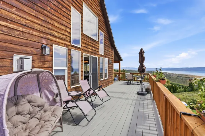 Expansive exterior deck featuring a wood-finish railing, a gray-toned deck surface, and multiple windows along the home's wood-paneled siding