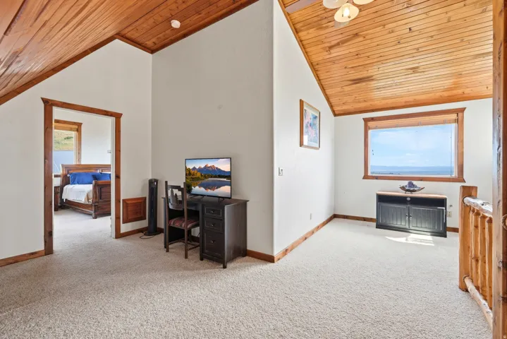 Carpeted upper level with wood-paneled vaulted ceilings and natural wood trim throughout
