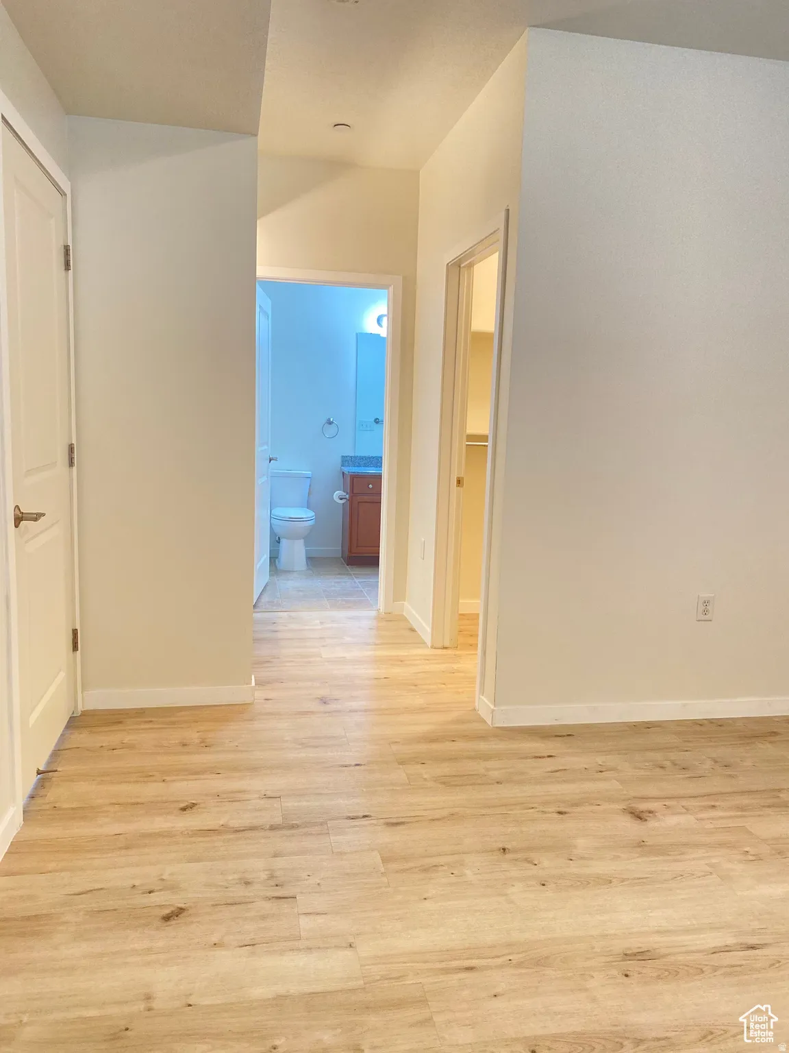 Hallway featuring light wood-finish flooring, neutral-toned walls, and white trim