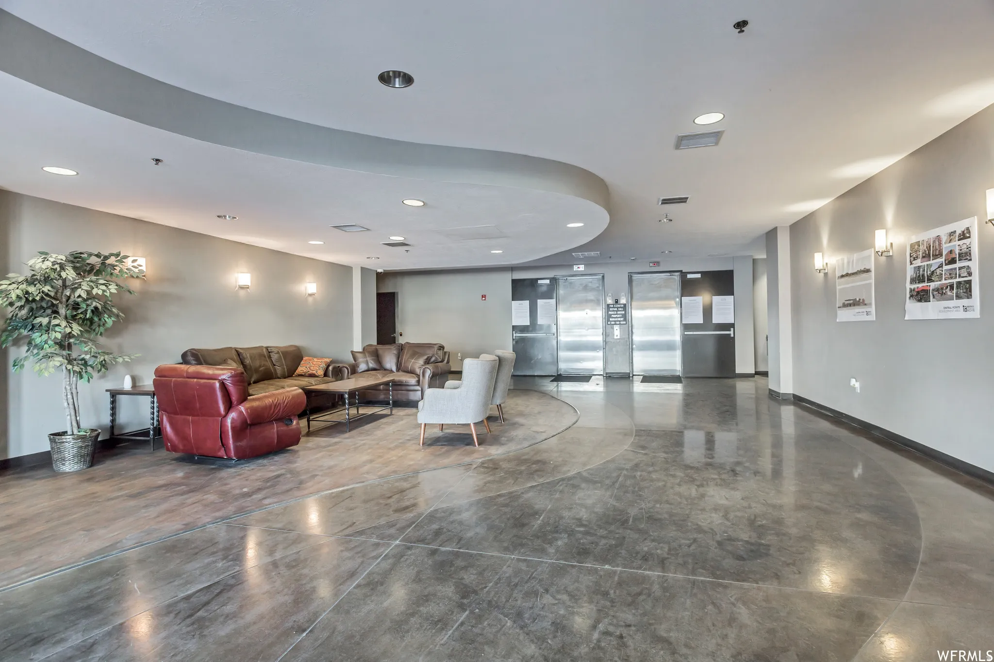 Polished concrete flooring with a circular inlay, complemented by recessed lighting and wall sconces
