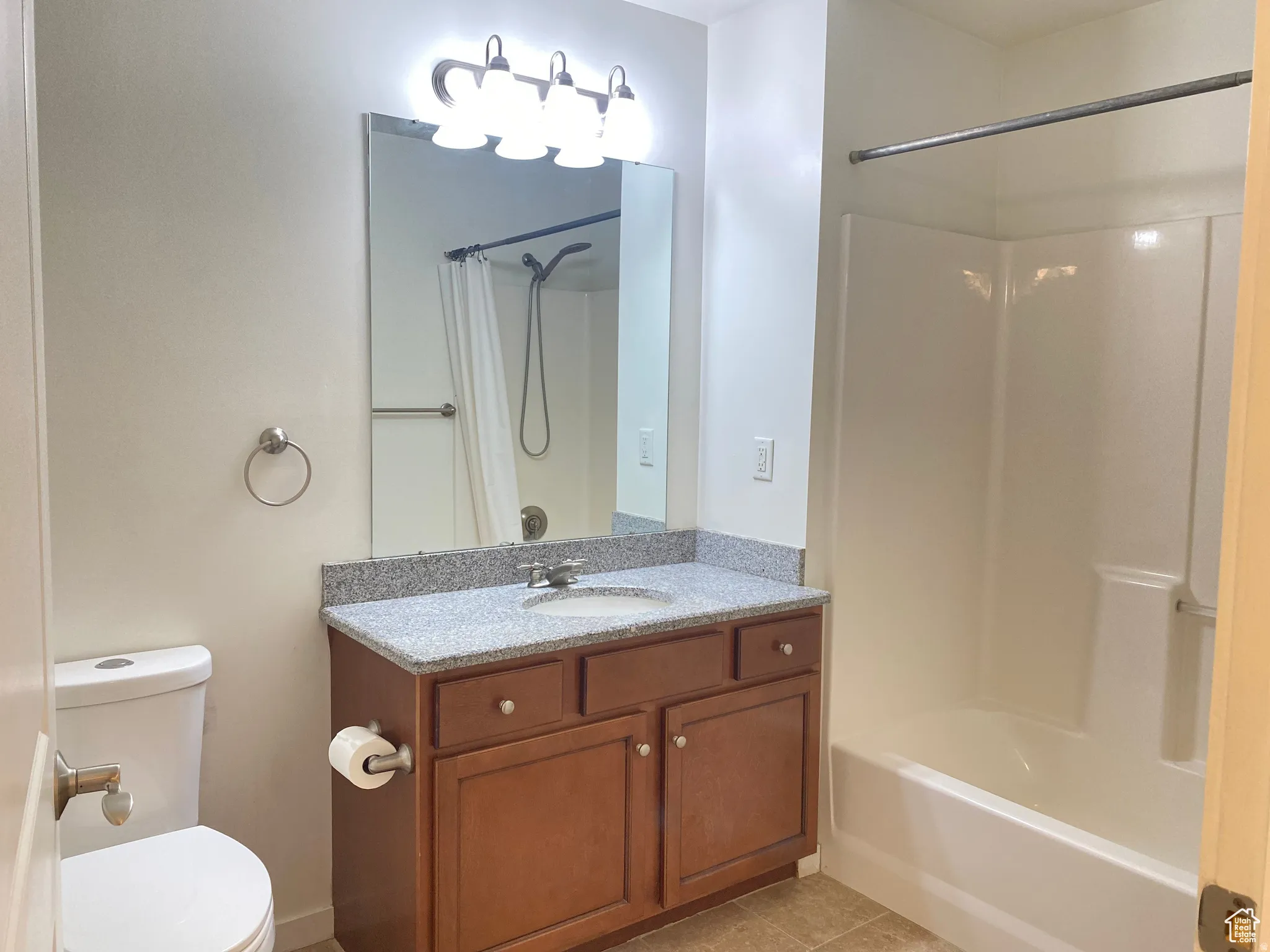 Full bathroom featuring a single vanity with a granite-style countertop, integrated sink, and wood-finish cabinetry
