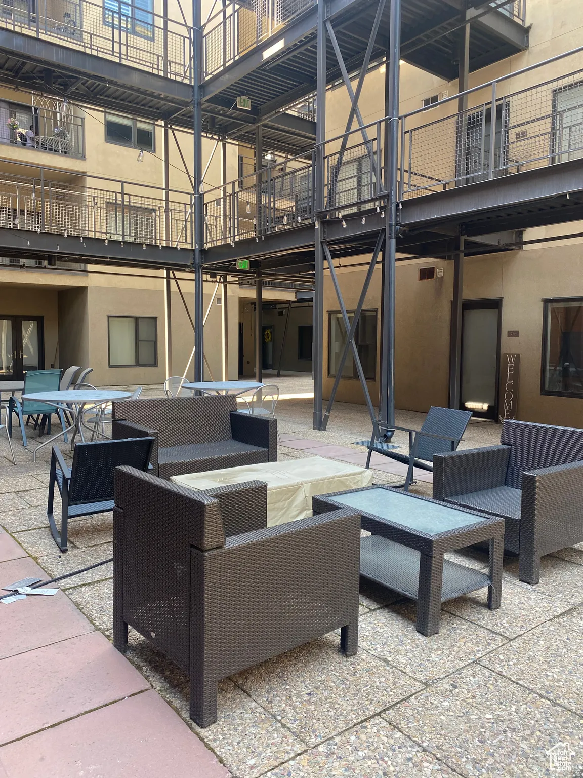 Exterior courtyard featuring multi-level open-air walkways with metal railings and mesh infill