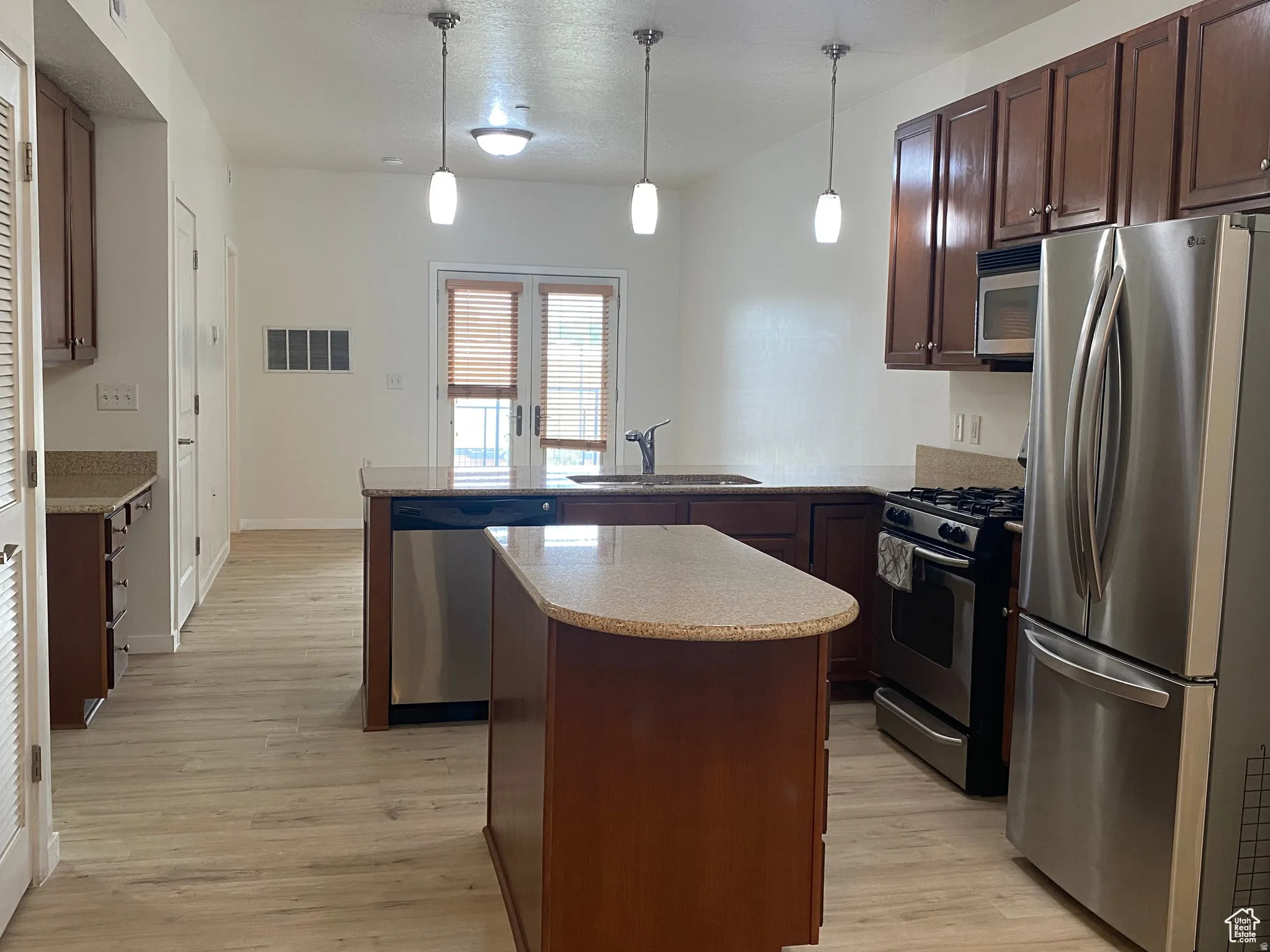 Kitchen featuring wood-finish flooring, dark wood cabinetry, and speckled countertops