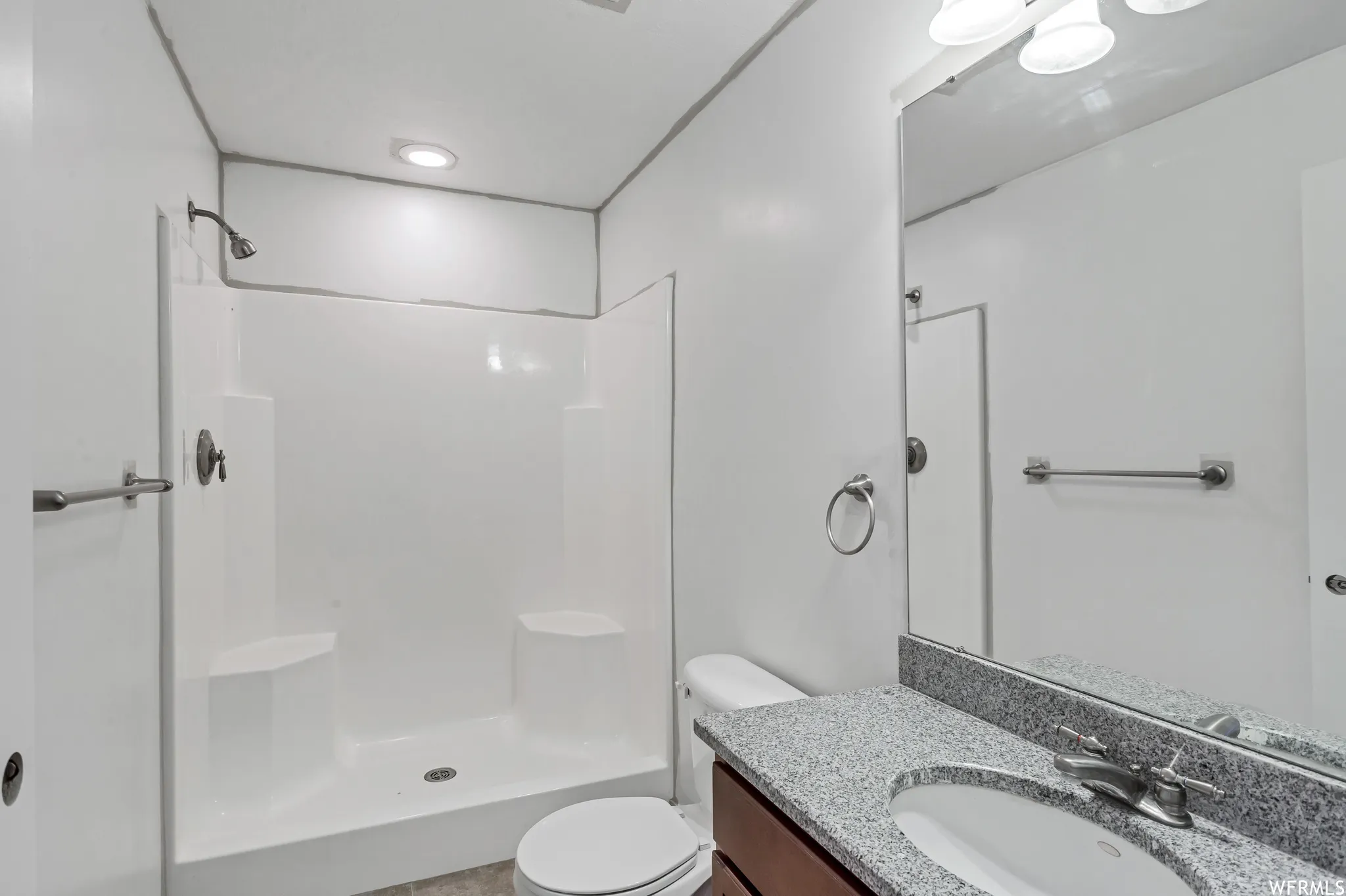 Bathroom featuring a shower-tub combination, a vanity with a stone-finish countertop, an undermount sink, and a framed mirror