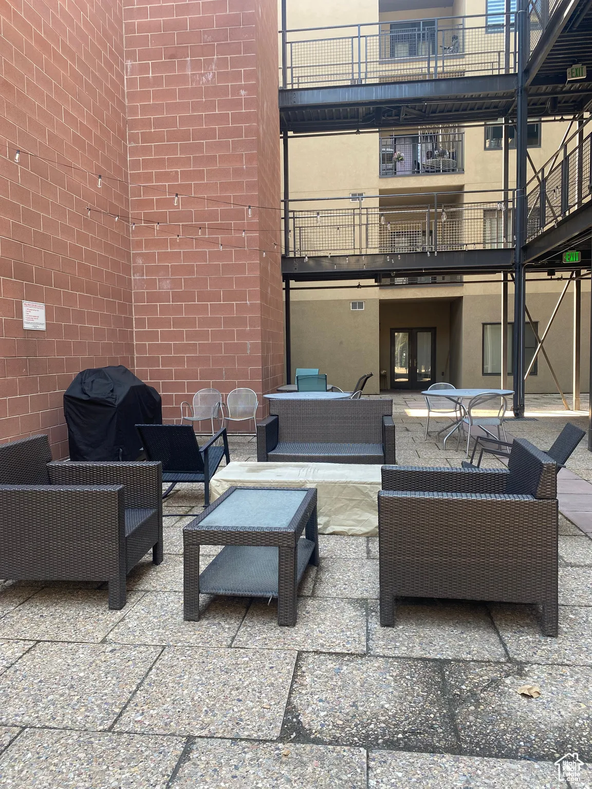 Expansive paved courtyard featuring string lighting and a durable brick wall