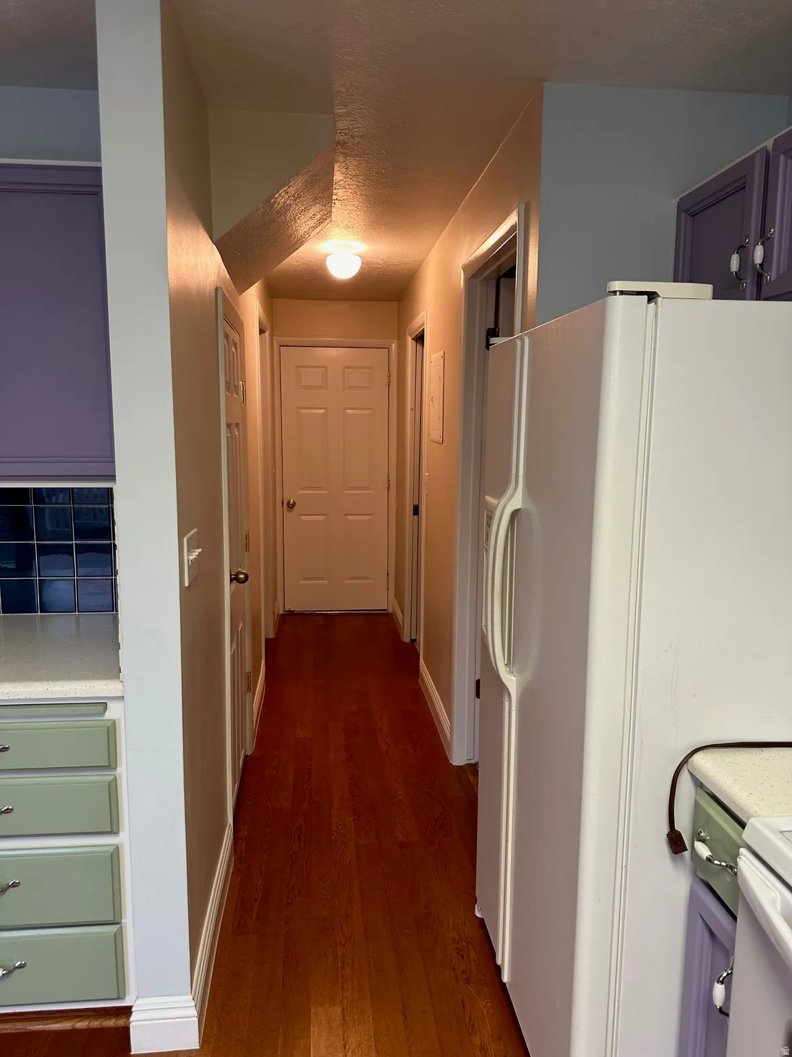 Hallway featuring wood-finish flooring, flush mount lighting, and white baseboards