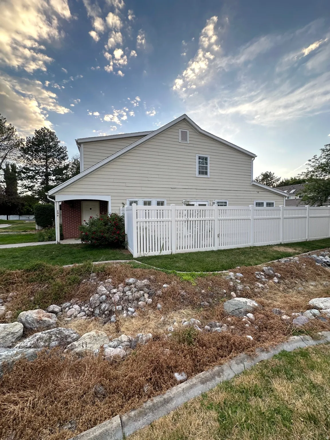 Two-story residence featuring light-colored siding and a white vinyl fence
