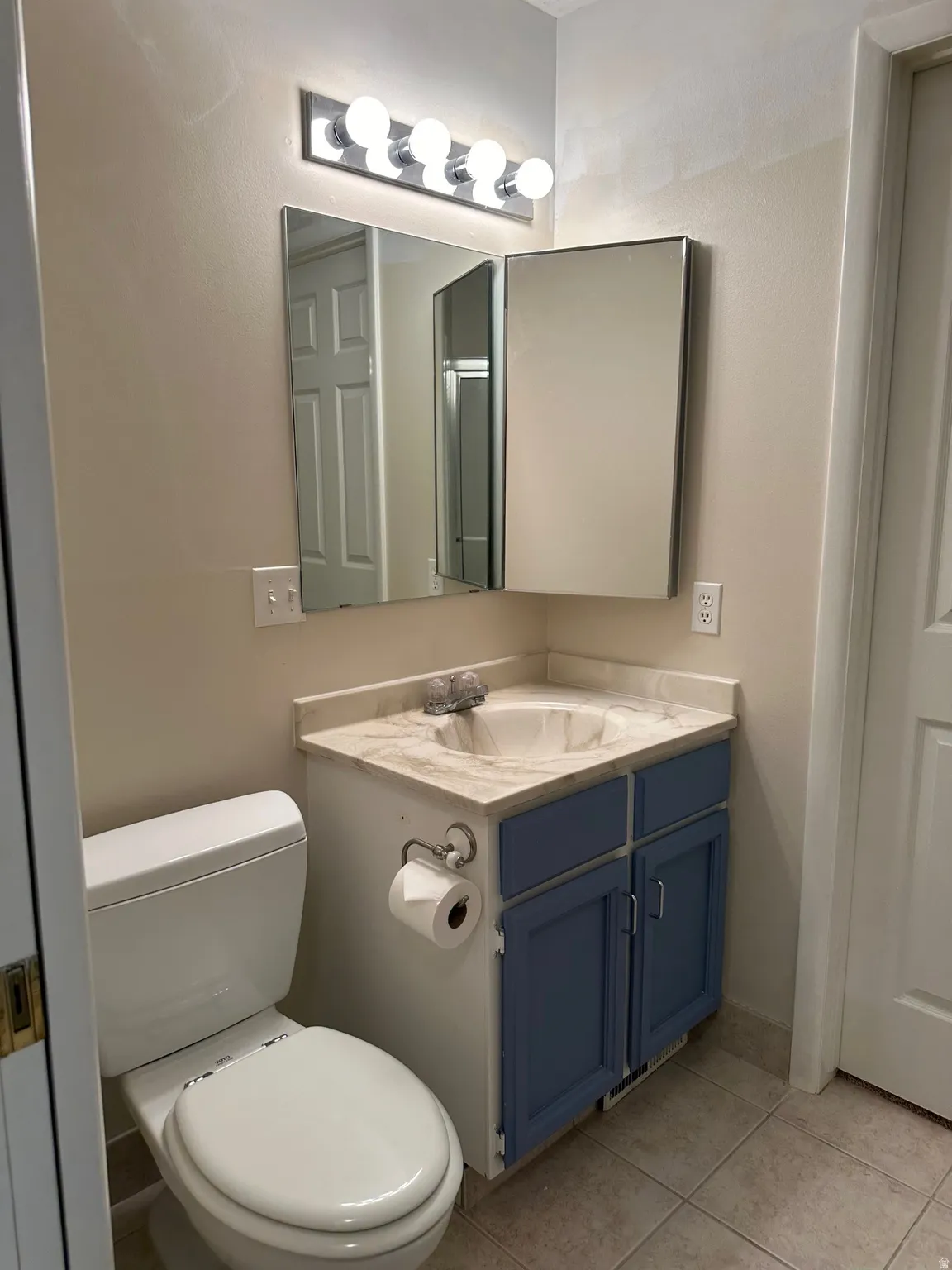 Bathroom vanity with a cultured marble countertop, integrated sink, and painted blue cabinetry