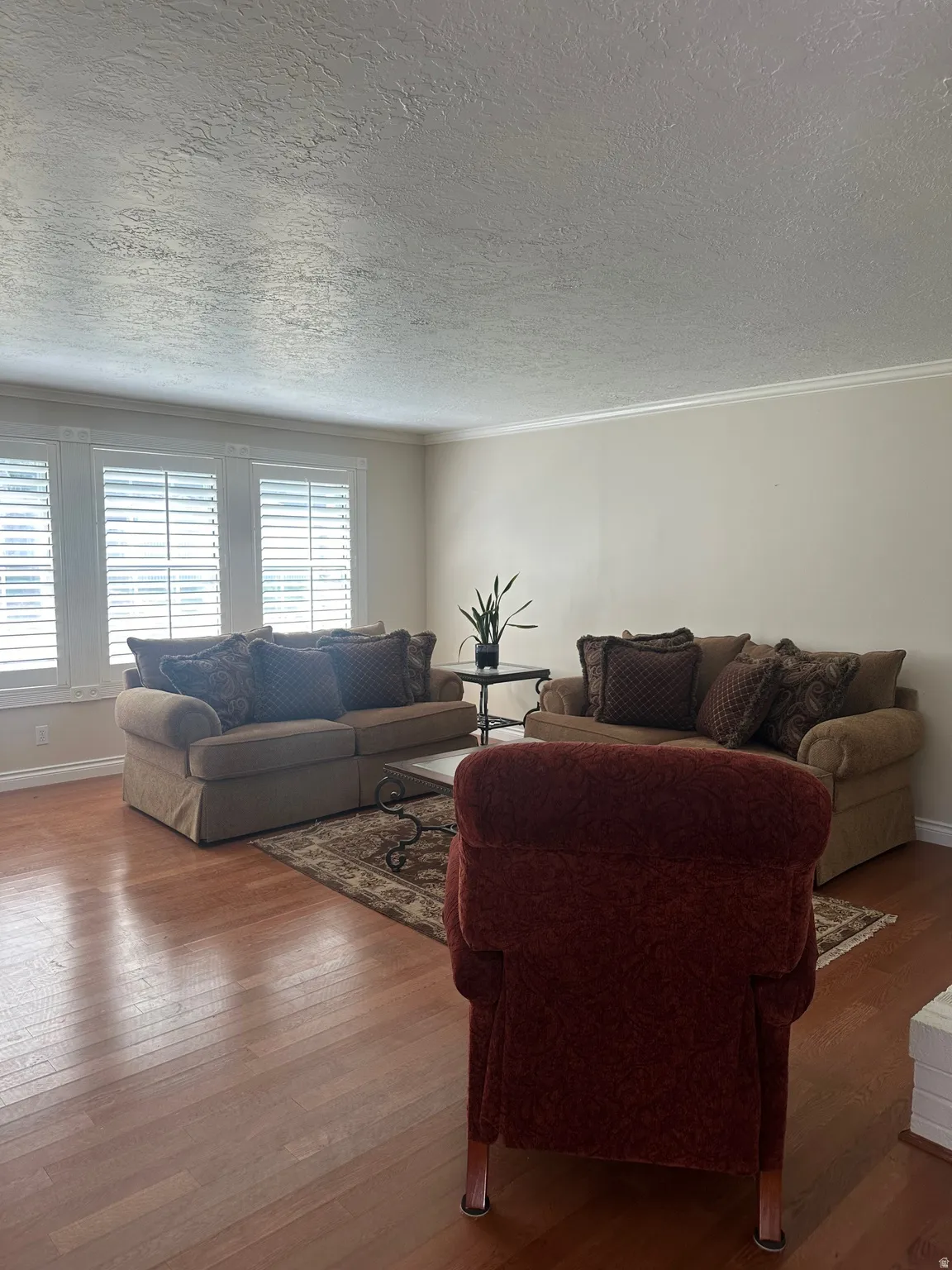 Wood-finish flooring, white window shutters, and white crown molding