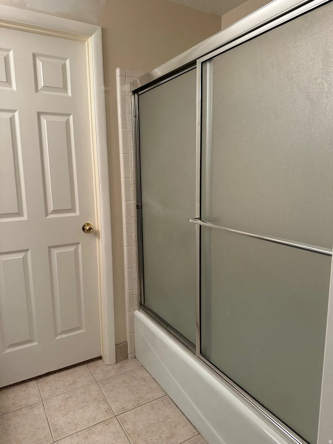 Bathtub with sliding frosted glass enclosure and chrome framing