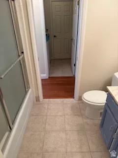 Bathroom featuring a tub with sliding glass doors, tile flooring, and a vanity with a light-colored countertop