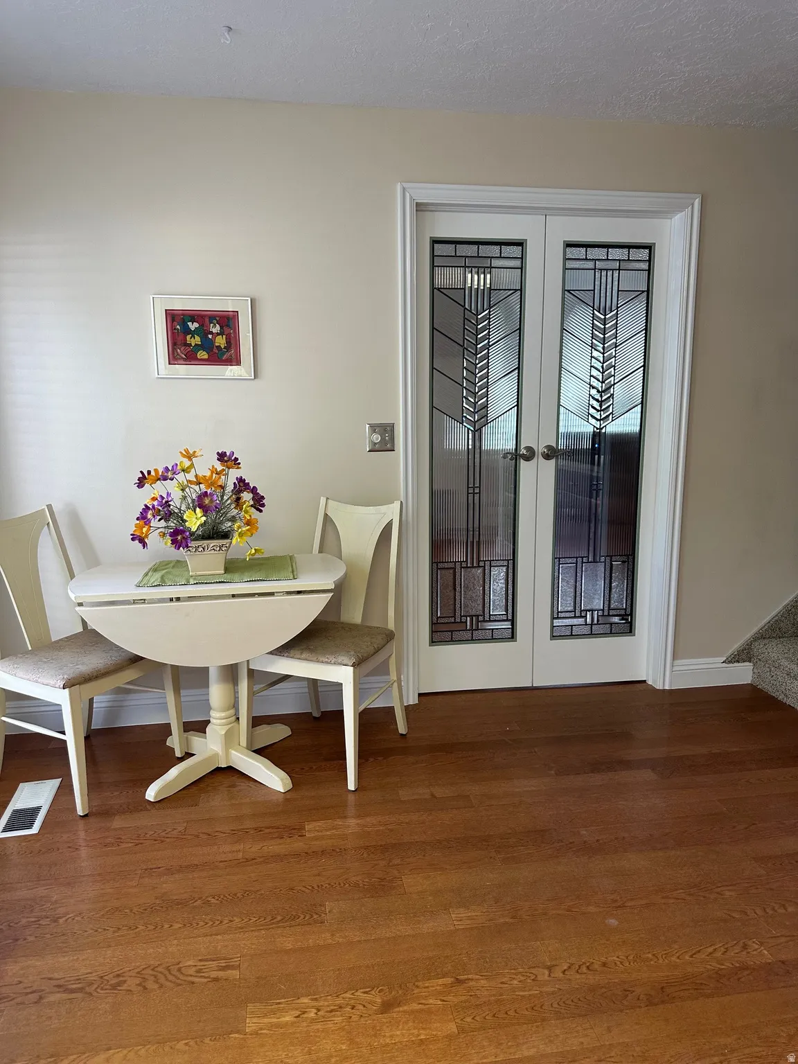 French doors with decorative glass panels, wood-finish flooring, and white trim accents