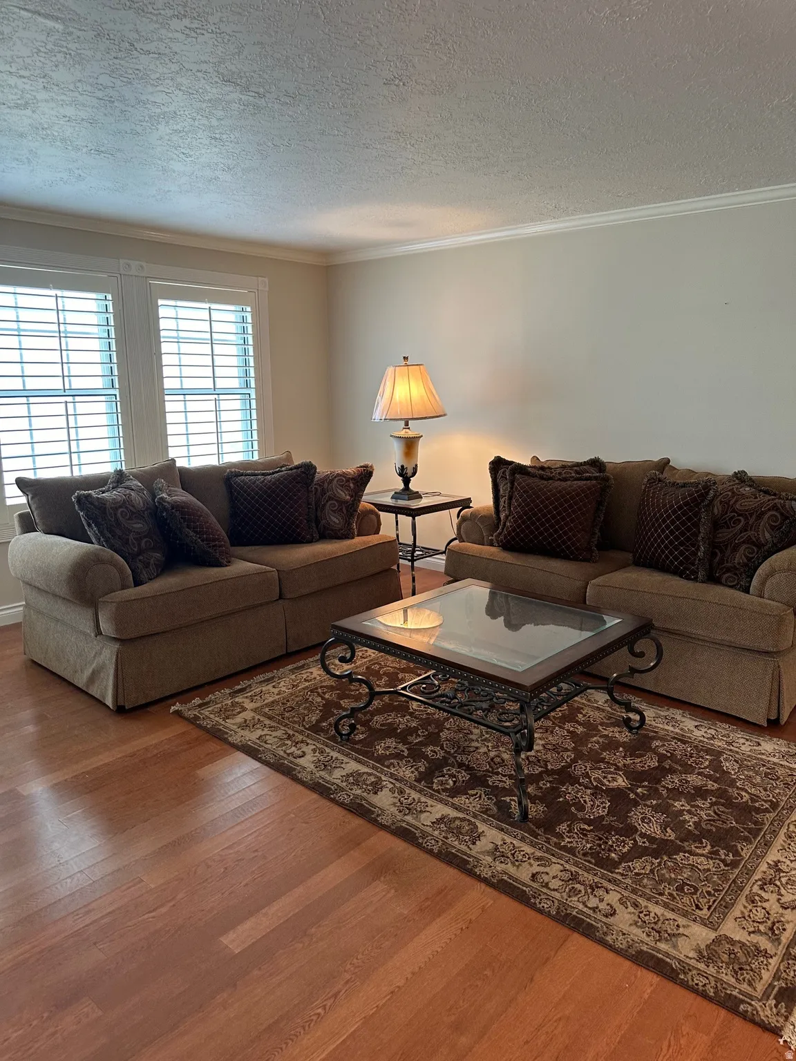 Expansive living area featuring warm wood-finish flooring, white crown molding, and neutral wall tones