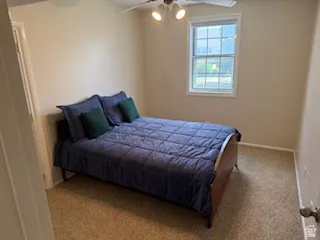 Carpeted room featuring a ceiling fan with integrated lighting, neutral wall paint, and a double-pane window
