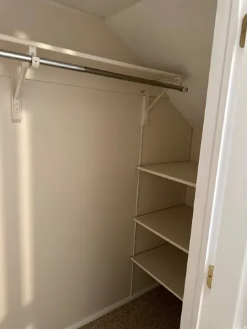 Built-in closet shelving and hanging rod provide storage in second bedroom closet.