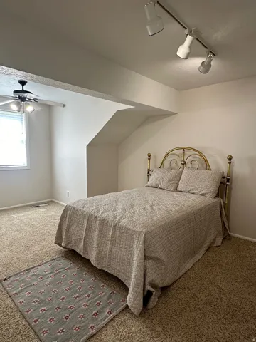 Carpeted flooring, ceiling fan with integrated lighting, recessed window, and ceiling-mounted track lighting