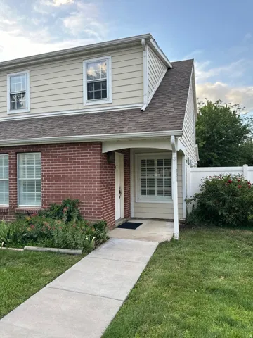 Brick and siding exterior featuring a covered entry, gabled roof, and a concrete walkway