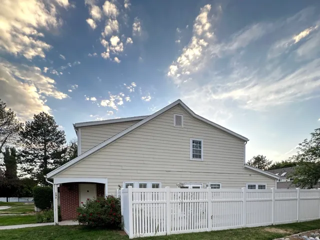 Two-story residence featuring light-colored siding and a white vinyl fence