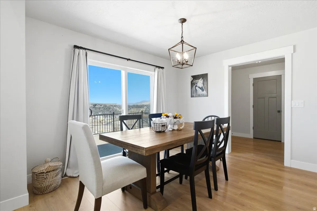 Dining area featuring a large window with distant scenery, wood-finish flooring, a contemporary chandelier, and a framed doorway