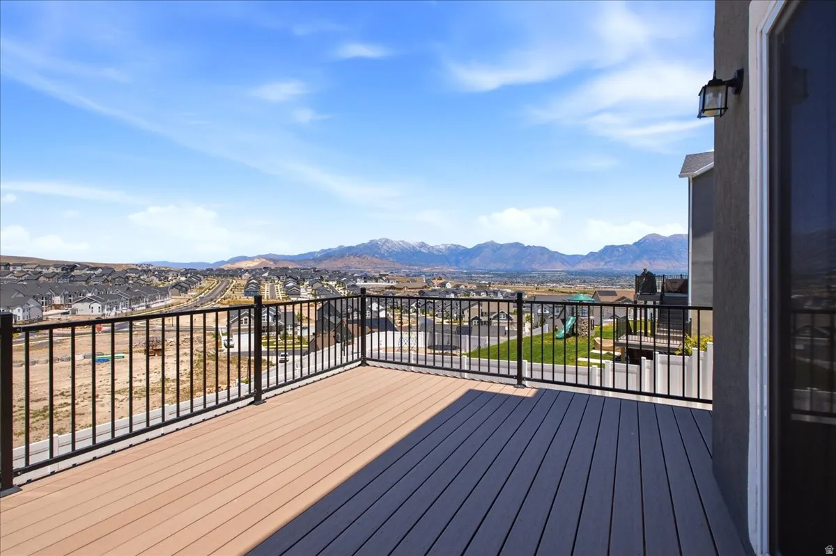 Expansive outdoor deck featuring wood-finish composite decking, black metal railing, and an exterior wall light fixture