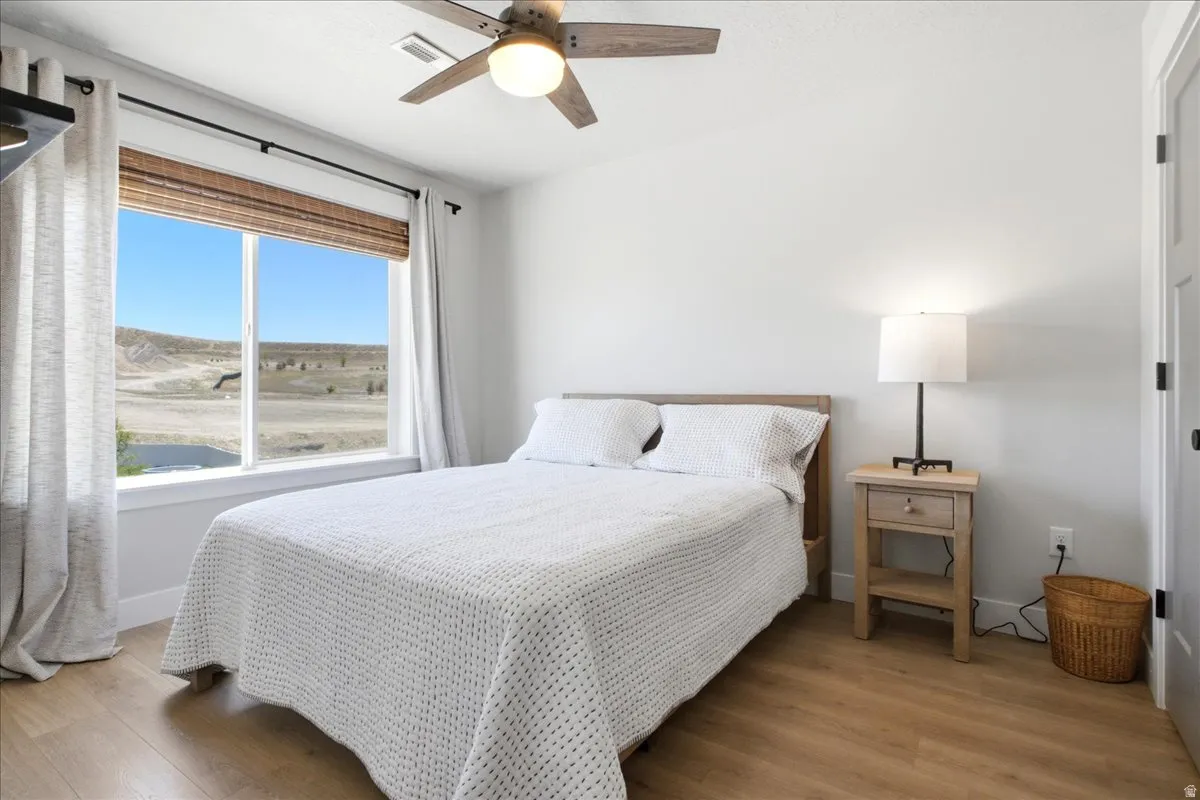Light-filled room featuring wood-finish flooring and a ceiling fan with integrated lighting