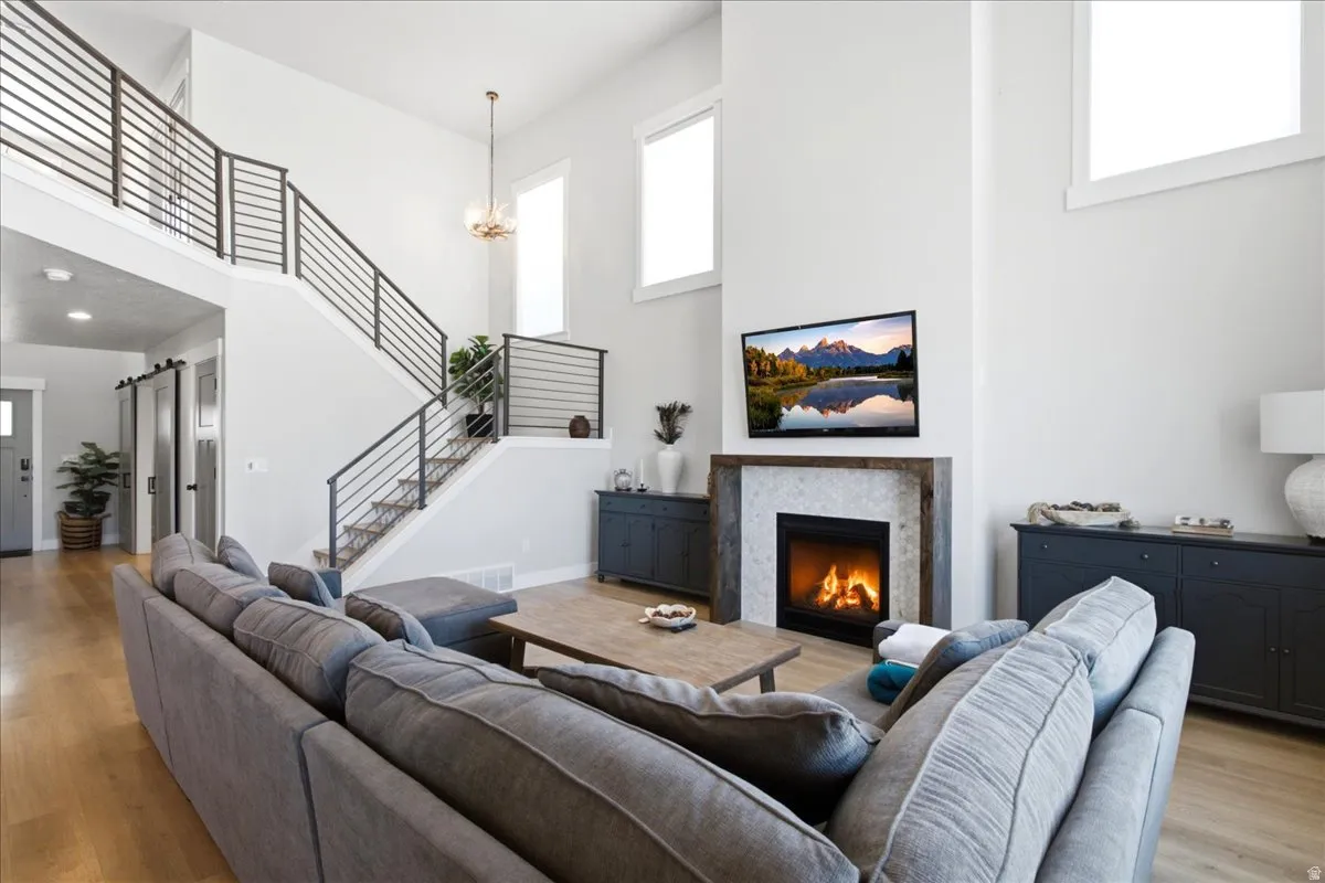 Spacious living room featuring high ceilings, wood-finish flooring, and a modern fireplace with a tiled surround and wood mantel