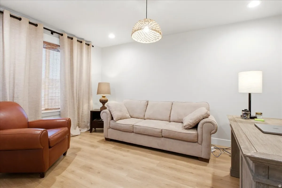Spacious room with light wood-finish flooring, recessed lighting, and a woven pendant light fixture
