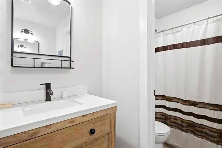 Bathroom vanity featuring a wood-finish cabinet, integrated white sink, and a matte black single-handle faucet