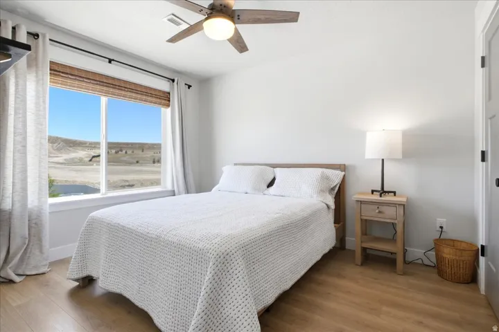 Light-filled room featuring wood-finish flooring and a ceiling fan with integrated lighting