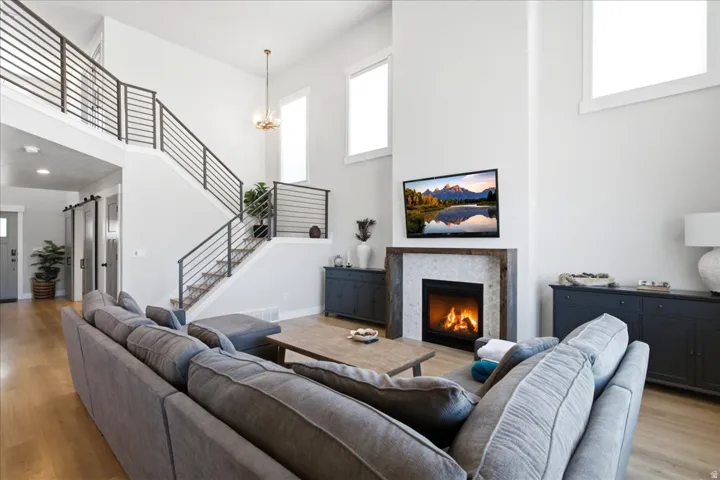 Spacious living room featuring high ceilings, wood-finish flooring, and a modern fireplace with a tiled surround and wood mantel