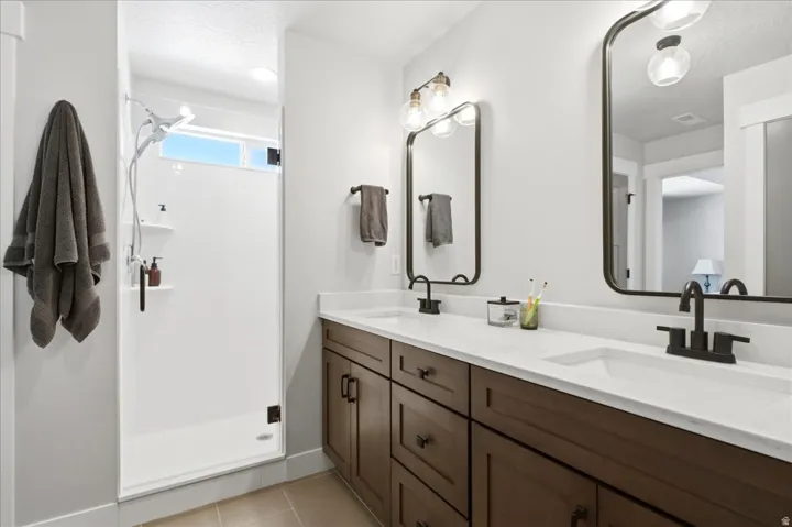 Modern bathroom featuring a dual vanity with dark wood-finish cabinetry, white countertops, and matte black fixtures