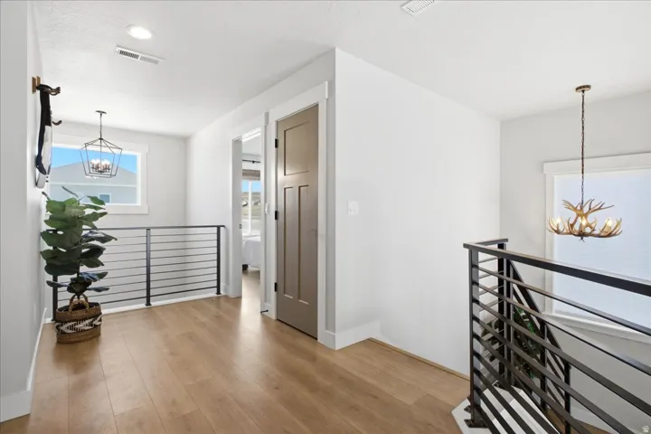 Upper-level landing featuring wood-finish flooring, white walls, and a modern horizontal bar railing system