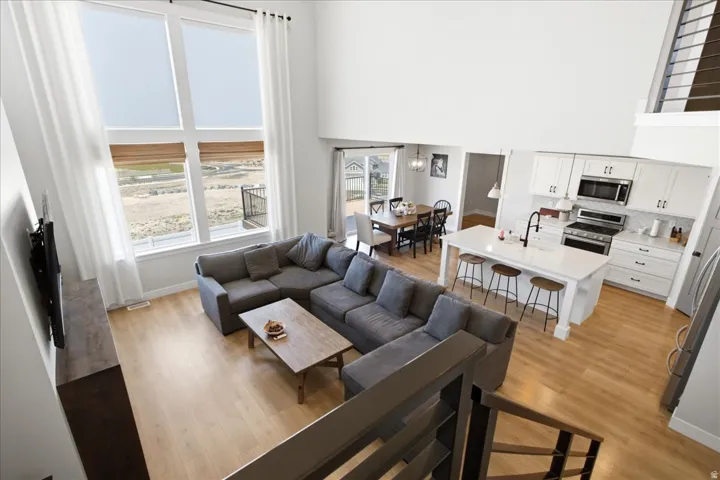 Open-concept living space featuring high ceilings, wood-finish flooring, and large windows with a scenic backdrop