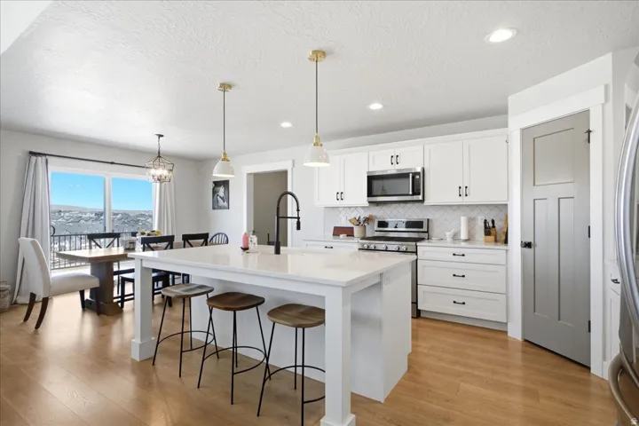 Kitchen featuring white cabinetry with dark hardware, a white subway tile backsplash, and stainless steel appliances