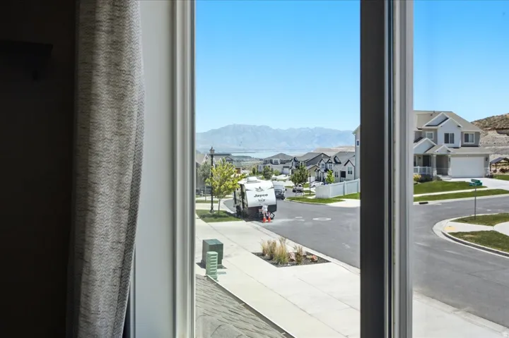 Window framing a community setting with paved streets, landscaped elements, and distant mountain scenery