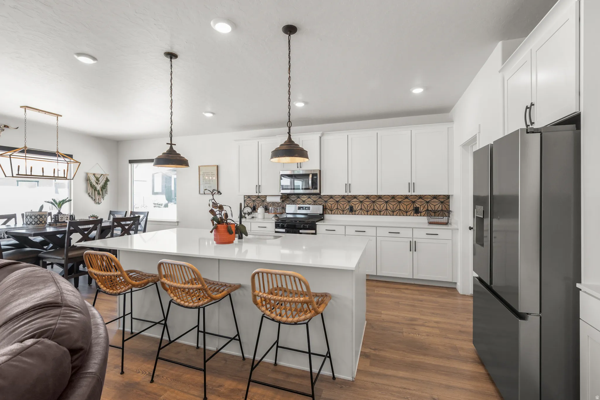 Modern kitchen featuring white cabinetry, a patterned backsplash, and stainless steel appliances